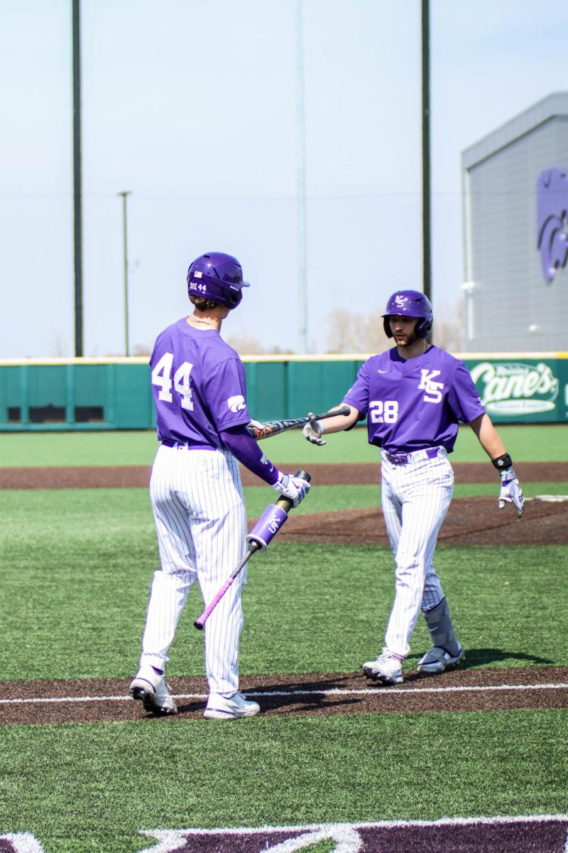 First baseman David Bishop hands a bat to catcher Raphael Pelletier. The Wildcats fell to the Longhorns 6-3 Saturday.