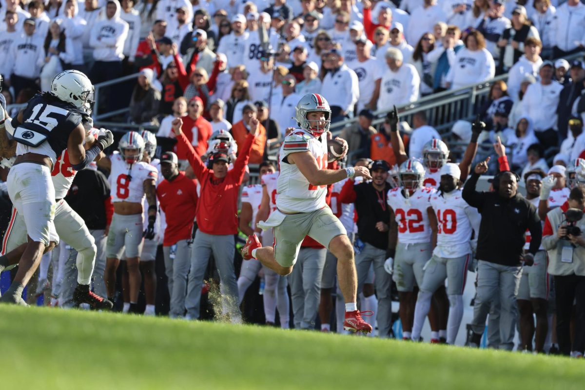 Graduate quarterback Will Howard carries the ball before a slide during the game against Penn State at Beaver Stadium on Nov. 2. The No. 4 Buckeyes claimed a 20-13 victory over the No. 3 Nittany Lions, earning a new No. 2 ranking. Howard collected over 200 total yards and threw two touchdowns in his homecoming win.