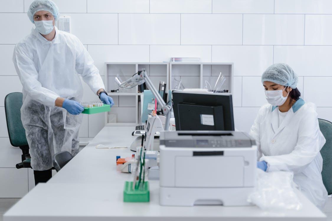 Free A Man and Woman in White Lab Gown Working Inside the Laboratory Stock Photo