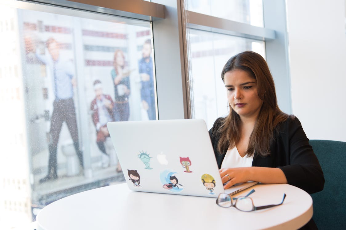 Free Focused woman using laptop in a modern office setting, working in tech development. Stock Photo